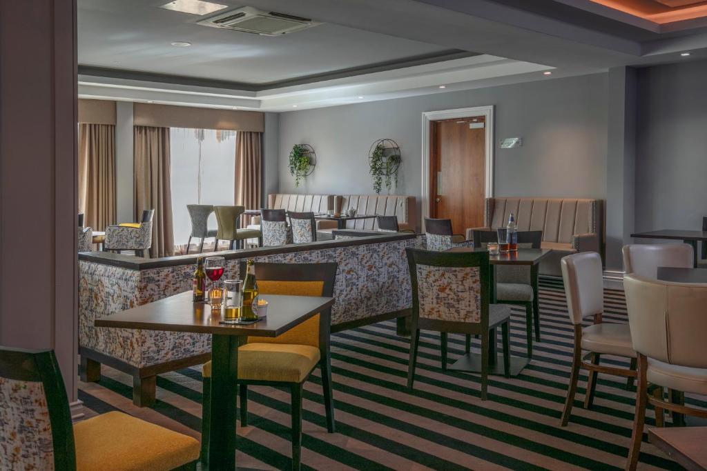 un restaurante con mesas y sillas y un bar en Best Western Appleby Park Hotel, en Tamworth