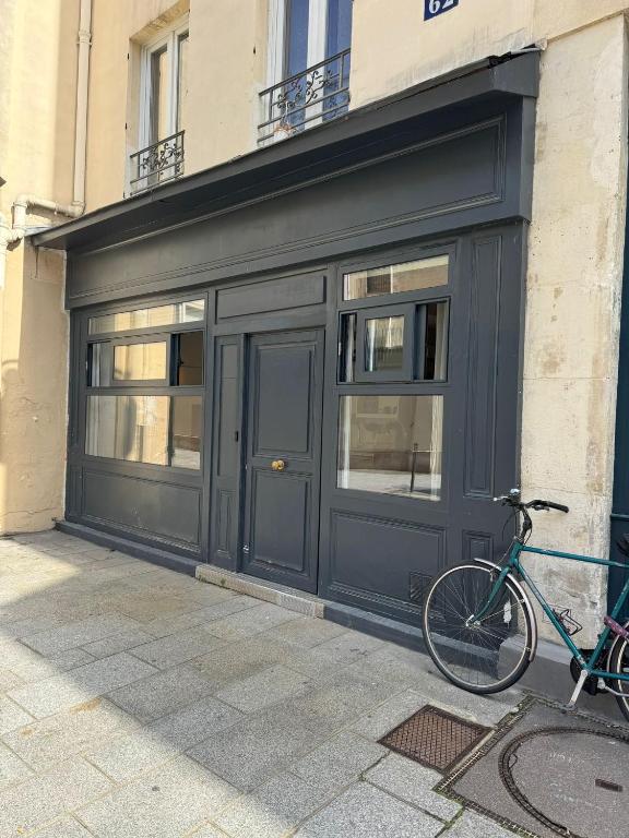 un vélo garé devant un garage noir dans l'établissement Ancien Atelier Parisien Grand 2 pièces, à Paris