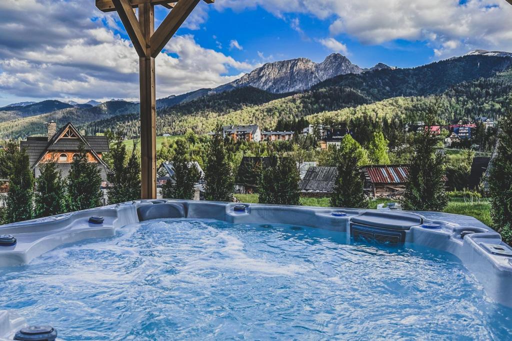 a hot tub with a view of mountains at TatryTop Osada Luxury Chalets Kościelisko in Kościelisko