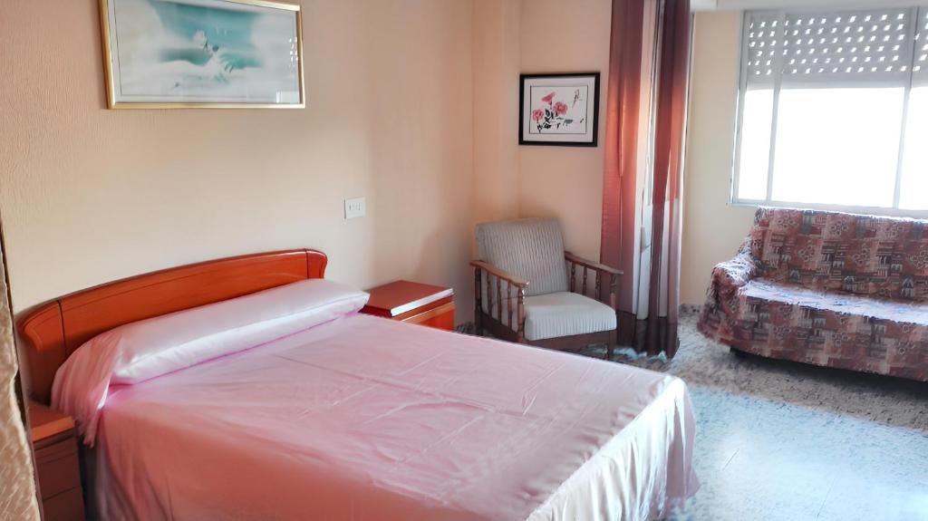 a bedroom with a bed and a chair and a window at 2 bedrooms apartement with city view and furnished balcony at Guardamar del Segura 1 km away from the beach in Guardamar del Segura
