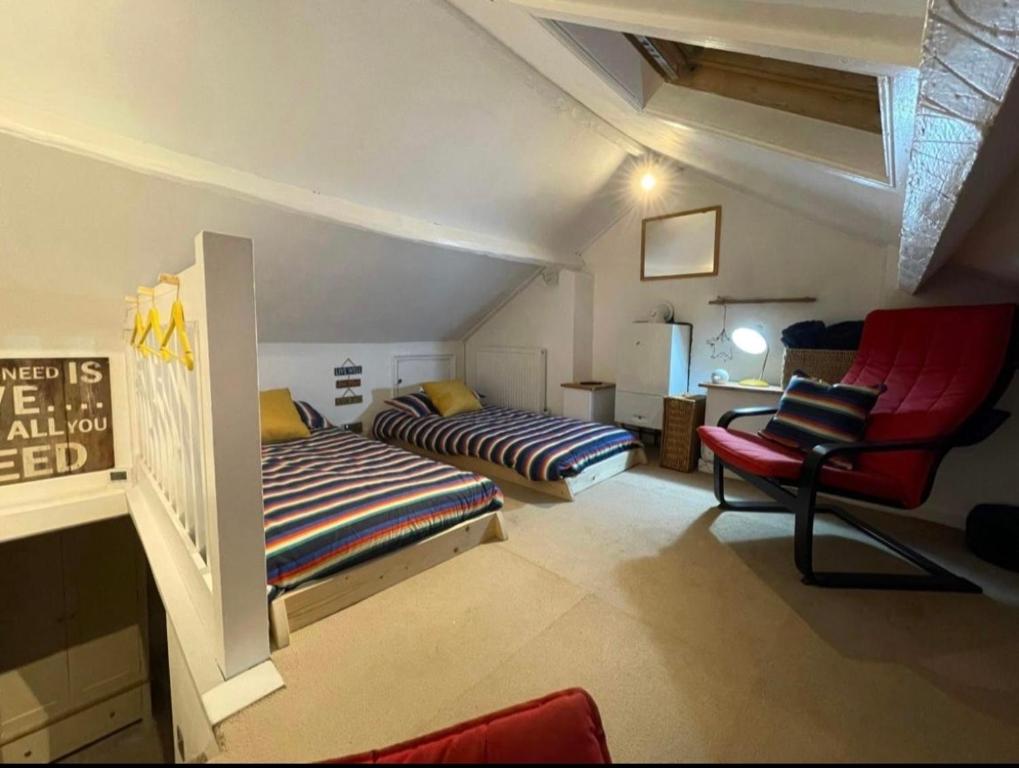 a attic room with a bed and a chair at Lotte’s Cottage in Bideford