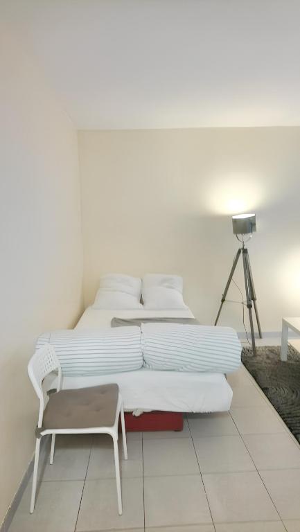 - une chambre blanche avec 2 lits et une chaise dans l'établissement Appartement d'une chambre avec terrasse et wifi a Les Pavillons sous Bois, à Les Pavillons-sous-Bois