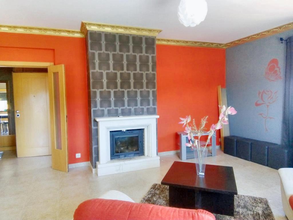 a living room with a fireplace and orange walls at 2 bedrooms apartement with enclosed garden and wifi at Urqueira in Urqueira