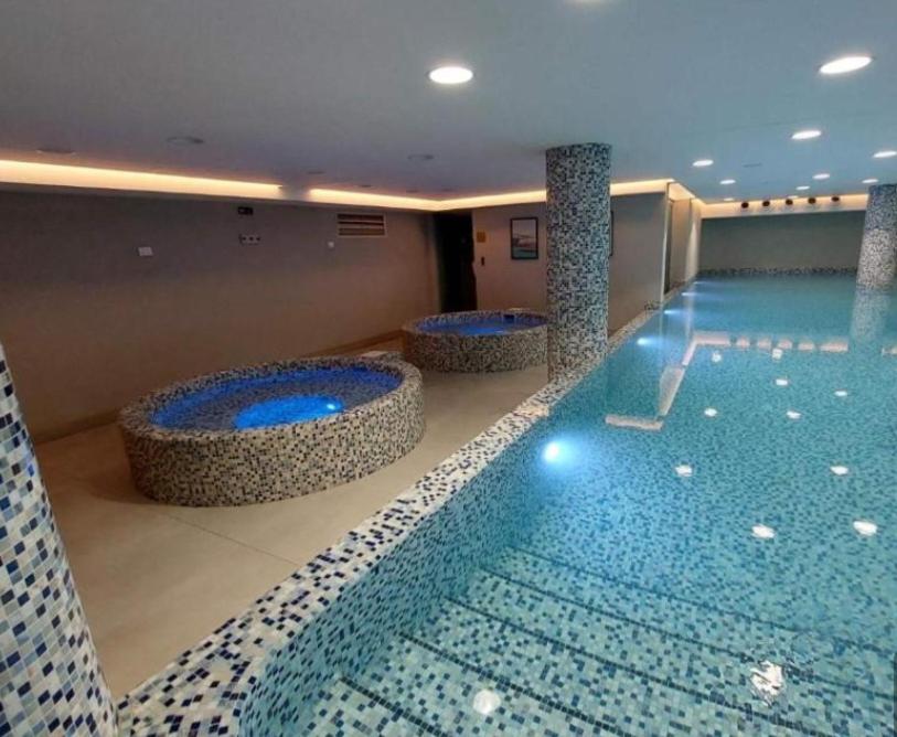 a large swimming pool with two jacuzzles in a building at Apartman Nada de lux in Vrnjačka Banja