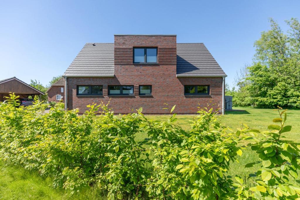 ein Backsteinhaus mit einem Dach auf einem grünen Feld in der Unterkunft Risum Huus in Risum-Lindholm
