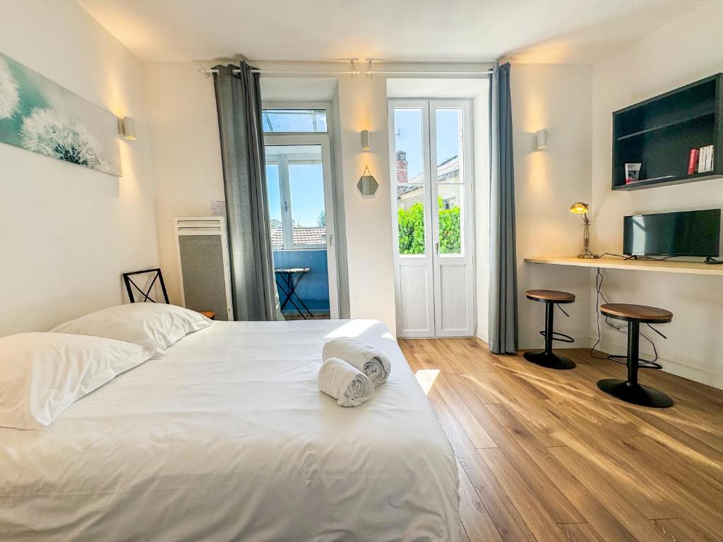 une chambre avec un lit blanc avec deux tabourets dans l'établissement Le Victor Hugo, à Périgueux