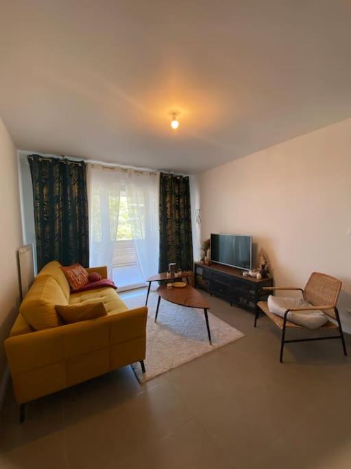 un salon avec un canapé jaune et une télévision dans l'établissement Appartement charmant à 10 minutes des plages, à Châteauneuf-les-Martigues