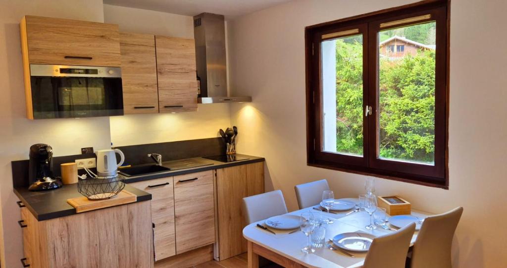 une cuisine avec une table et des chaises ainsi qu'une fenêtre dans l'établissement Appartement le Mont de Grange, à Châtel