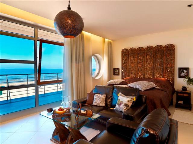 Boutique Hotel Light House Jurmala في يورمالا: غرفة نوم مع أريكة وسرير مع إطلالة على المحيط