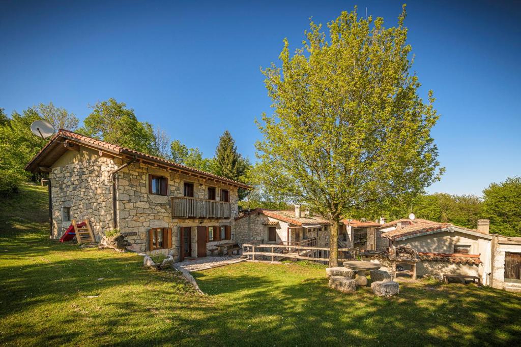 una casa de piedra con un árbol en el patio en Albergo Diffuso Forgaria Monte Prat, en Forgaria nel Friuli