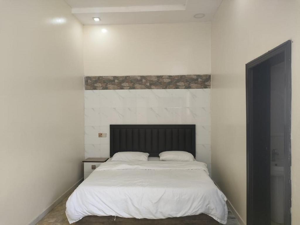 a bedroom with a white bed with a black headboard at استراحات توليب أبها in Qāʼid