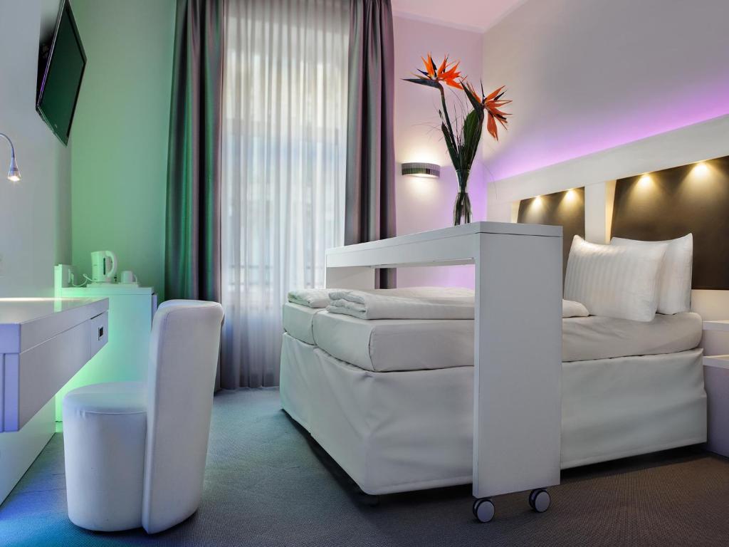 フランクフルト・アム・マインにあるグランド ホテル ダウンタウンのベッドルーム(白いベッド1台、白いソファ付)