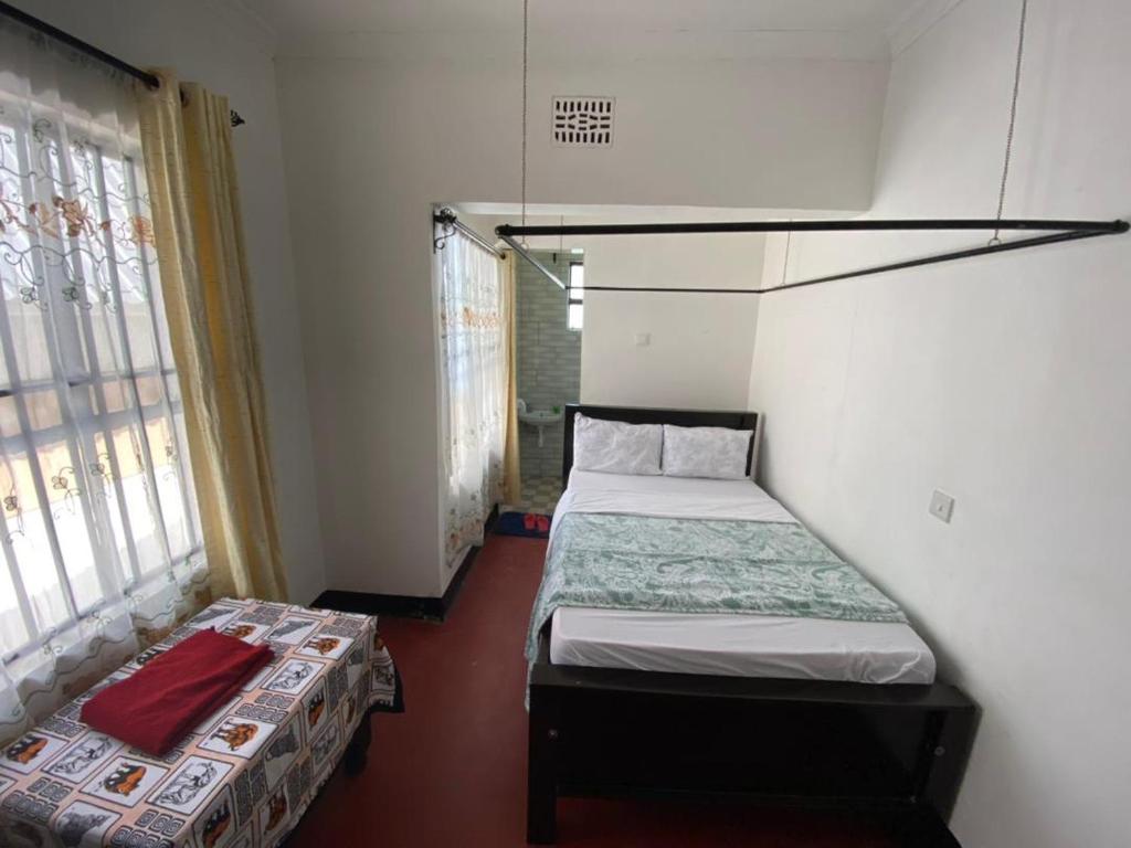 Una pequeña habitación con dos camas y una ventana. en vacation homes, en Arusha