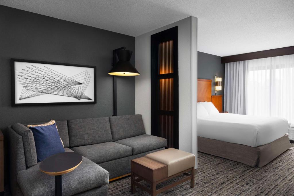 een hotelkamer met een bank en een bed bij Hyatt Place Detroit/Utica in Utica