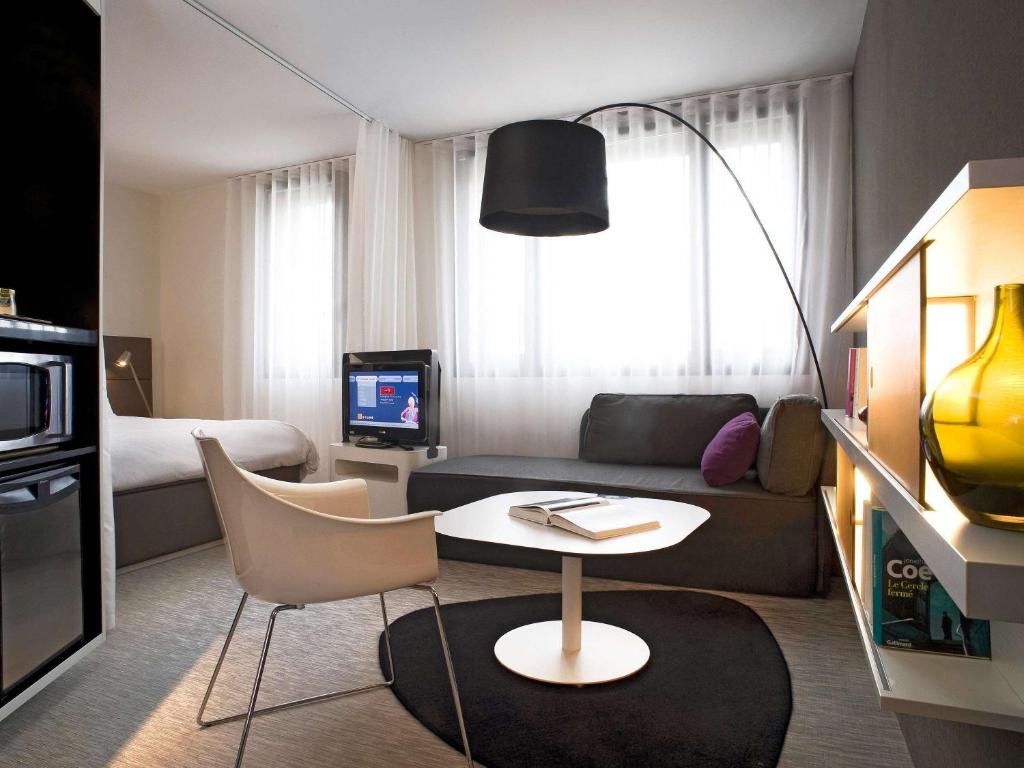 a living room with a couch and a table at Novotel Suites Perpignan Centre in Perpignan