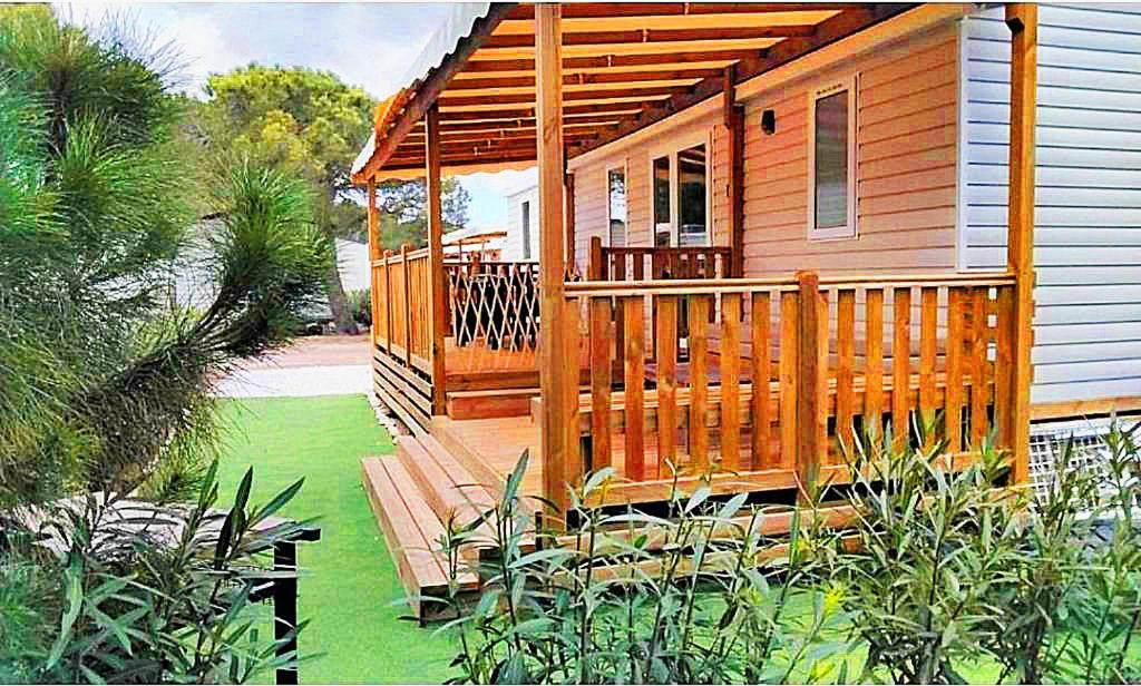 ein Haus mit einer Holzterrasse mit einer Veranda in der Unterkunft MH Luxury Eden Mar Estang Plage 100m 2TV 2 Sdb Baby confort Plus in Canet-en-Roussillon