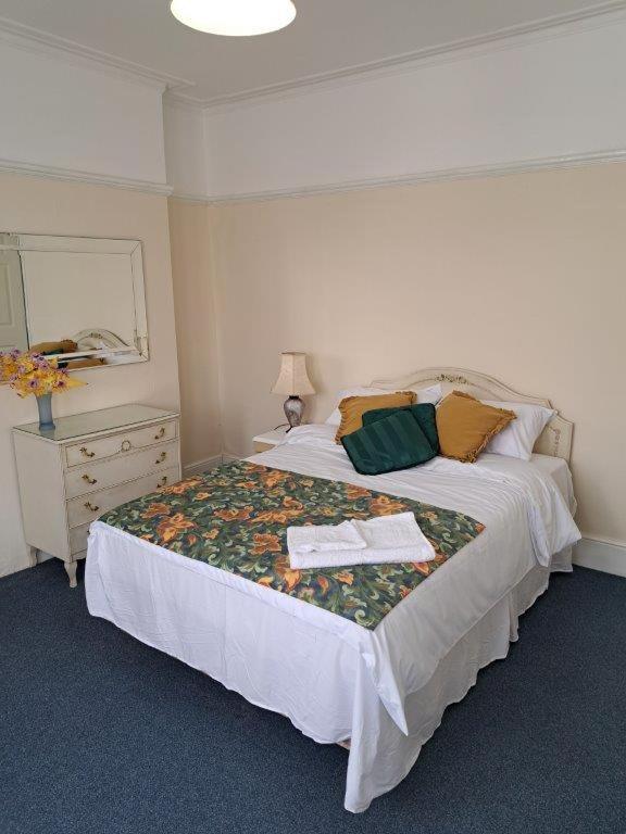 a bedroom with a large bed with a dresser and a mirror at London Town House in Seven Kings