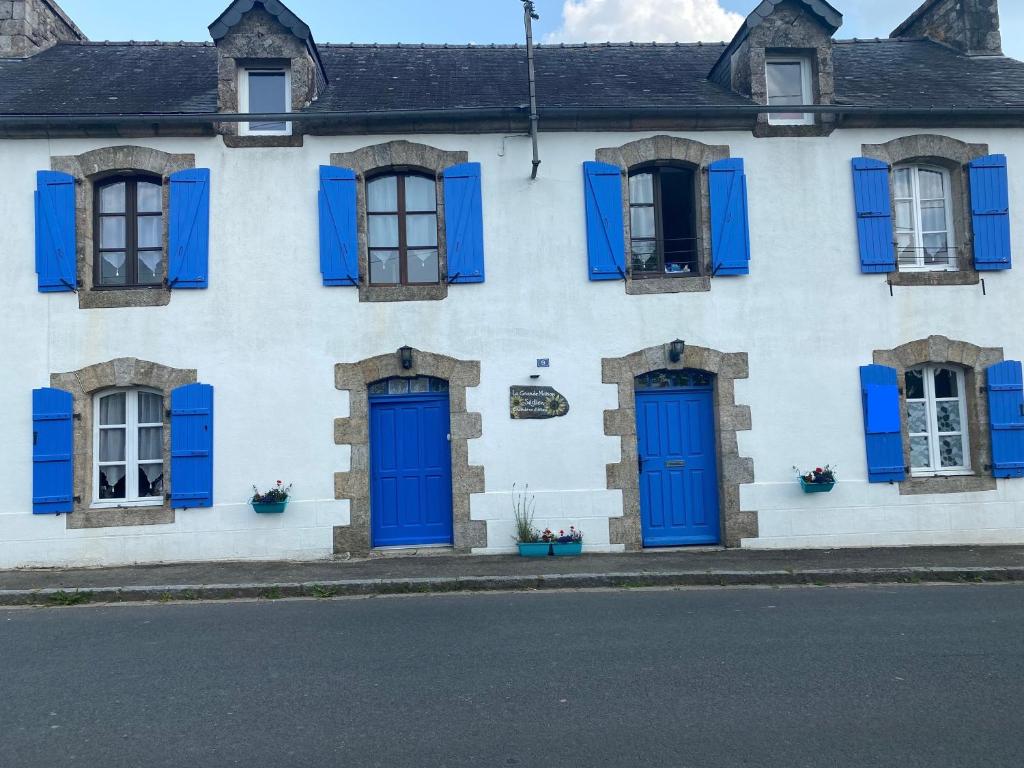 biały budynek z niebieskimi drzwiami i oknami w obiekcie La Grande Maison Seglien w mieście Séglien