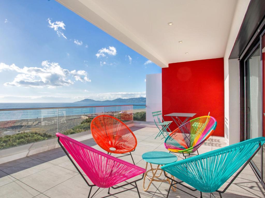 d'une terrasse avec des chaises colorées et une table sur un balcon. dans l'établissement Apartment La Palangre-1 by Interhome, à Argelès-sur-Mer