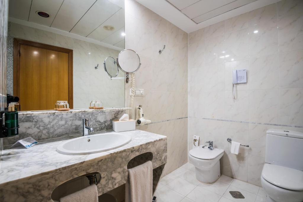 a bathroom with a sink and a toilet at Melia Plaza Valencia in Valencia