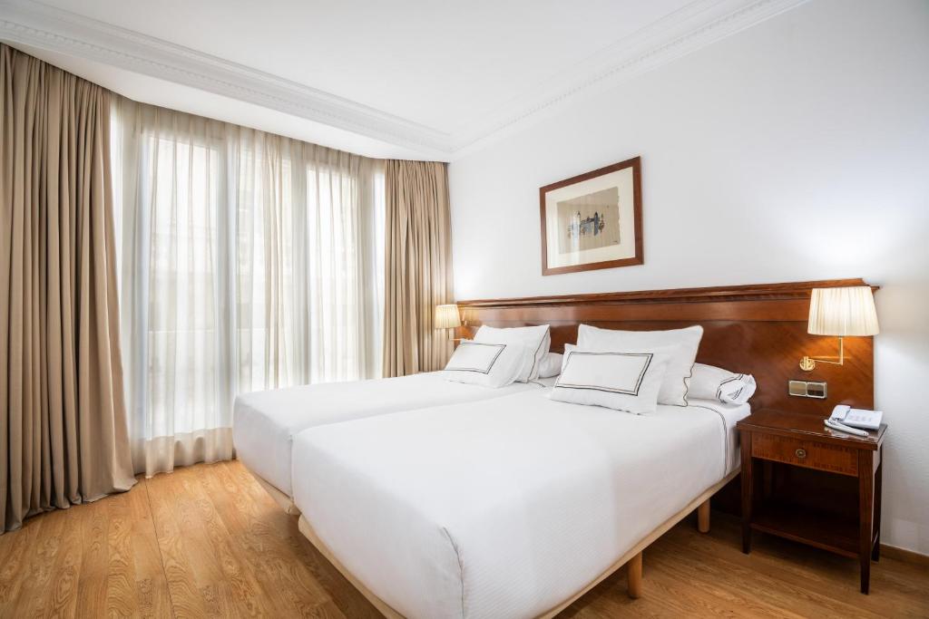 a bedroom with a large white bed and a window at Melia Plaza Valencia in Valencia
