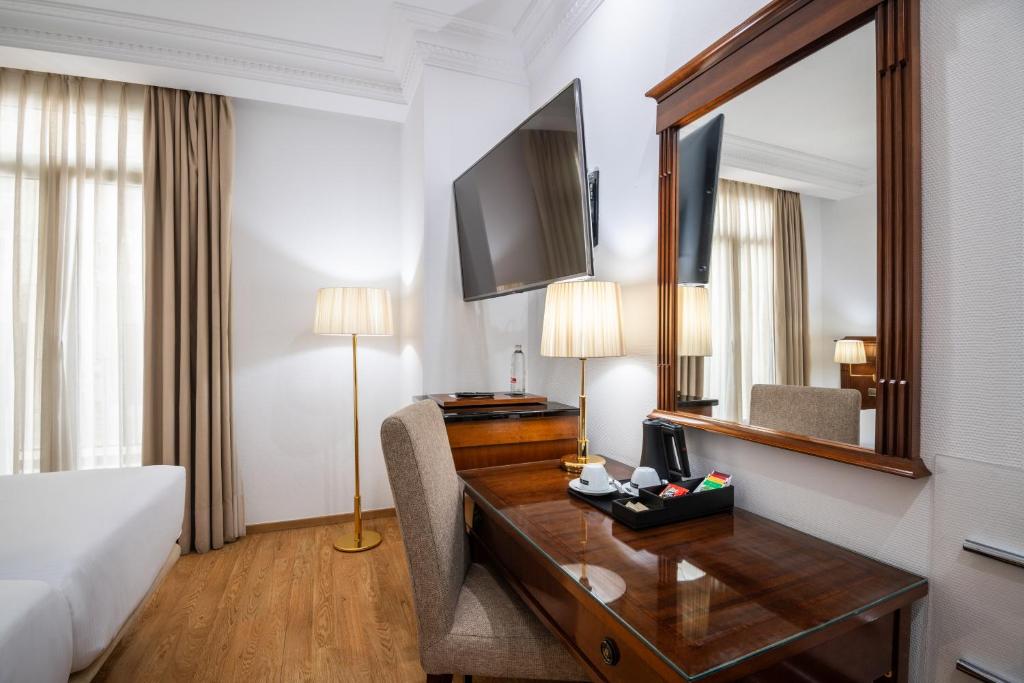 a hotel room with a desk and a bed at Melia Plaza Valencia in Valencia
