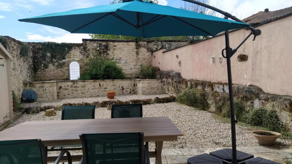 a table with a blue umbrella in a courtyard at Barn cottage in La Tour-Blanche