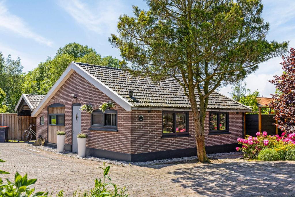 una casa de ladrillo con un árbol en la entrada en Vakantiehuisje Hoofdvaart, en Dedemsvaart