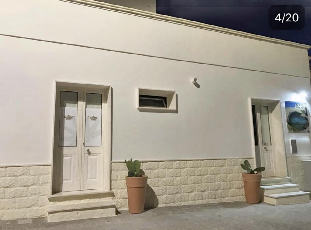 a white building with a door and two potted plants at One bedroom apartement with furnished terrace and wifi at Melendugno 5 km away from the beach in Melendugno