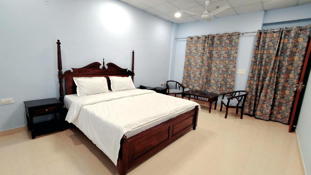 um quarto com uma cama grande com lençóis brancos e cortinas em Dev Sneh Residency em Jaipur