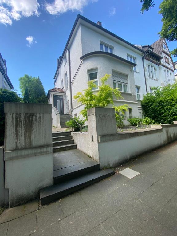 une maison blanche avec des escaliers en face de celle-ci dans l'établissement Souterrain Wohnung in einer Stadtvilla, à Hagen