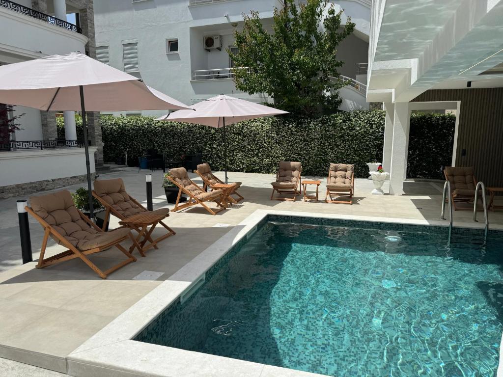 a swimming pool with chairs and umbrellas next to a building at Marini Casa in Ulcinj