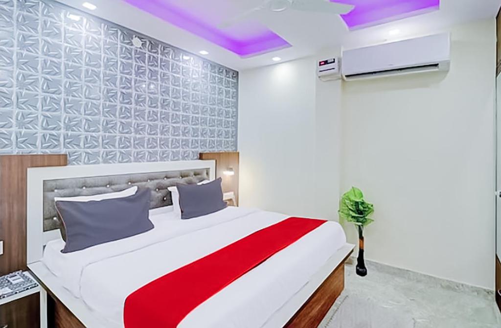 Hotel Green Pearl في نيودلهي: غرفة نوم بسرير أبيض مع بطانية حمراء