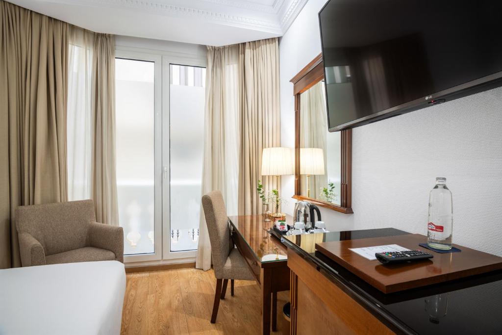 a hotel room with a desk and a bed at Melia Plaza Valencia in Valencia