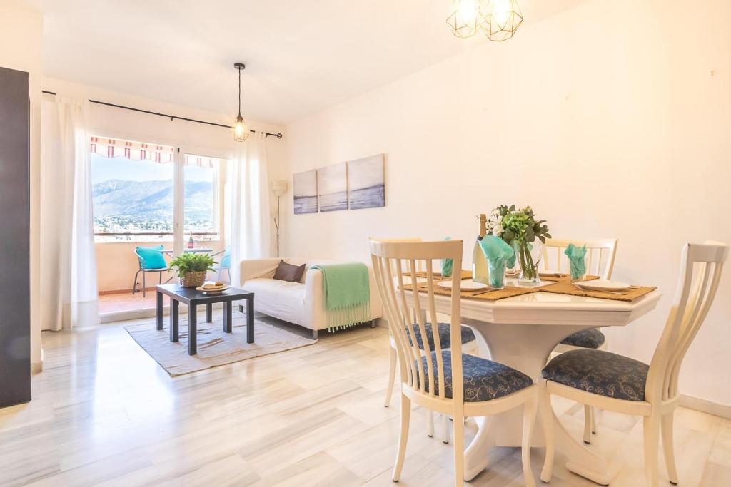 a dining room and living room with a table and chairs at Apt Parque Fuengirola 800mt From Sea - Happy rentals in Fuengirola