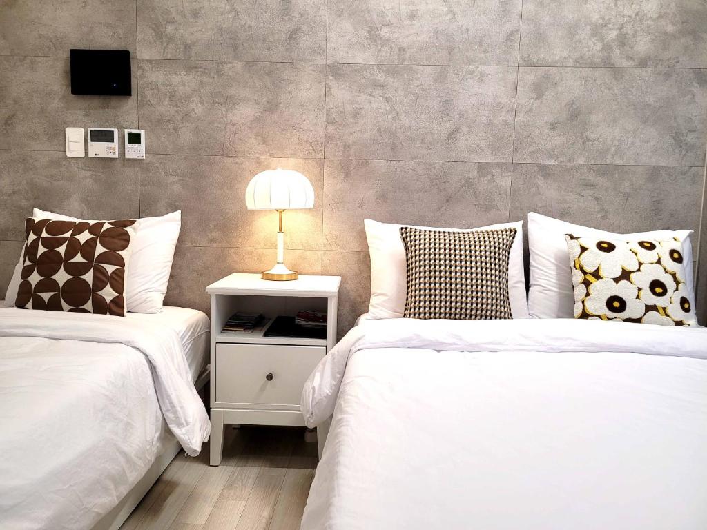 1 dormitorio con 2 camas y mesita de noche con lámpara en Elliy's Room en Busan