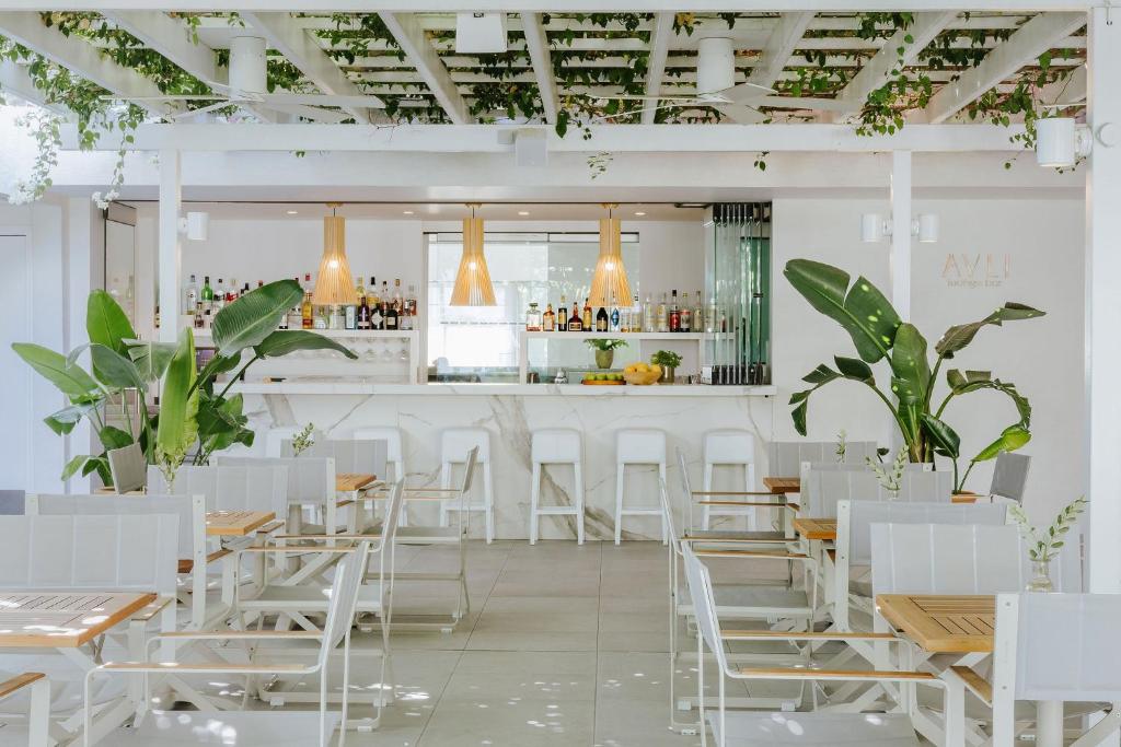 a restaurant with white tables and chairs and a bar at Nissi Park Hotel in Ayia Napa