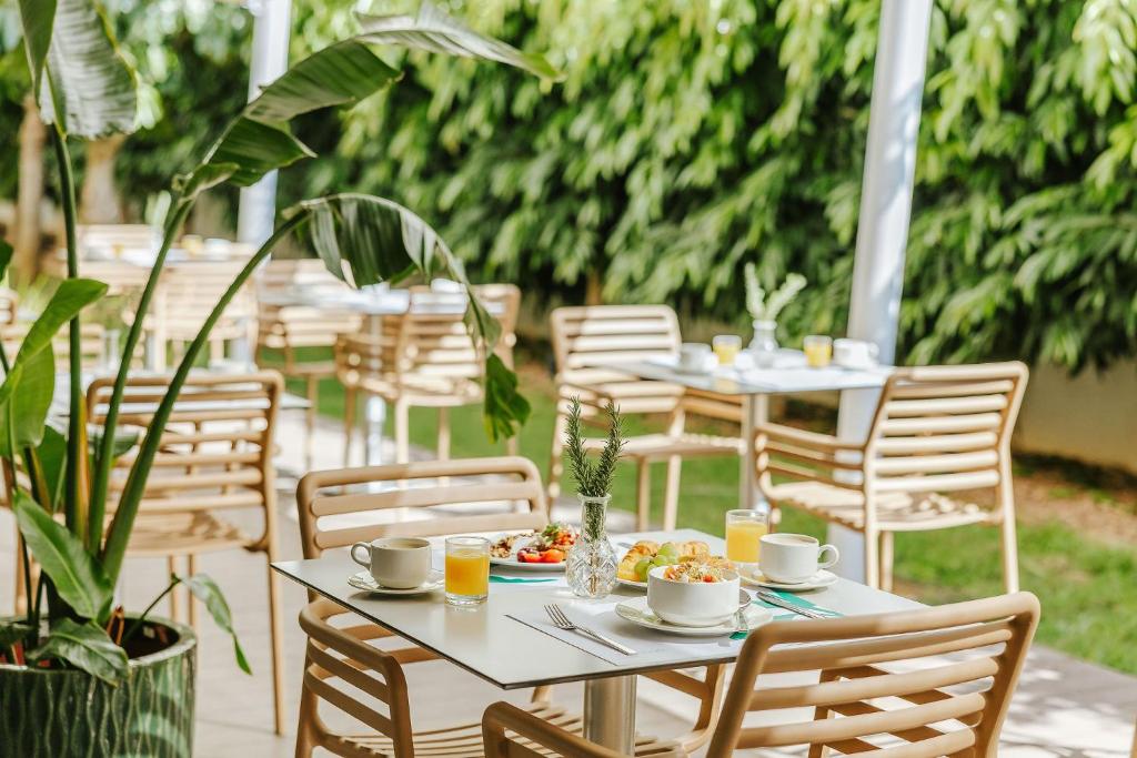 a table with plates of food and cups and chairs at Nissi Park Hotel in Ayia Napa