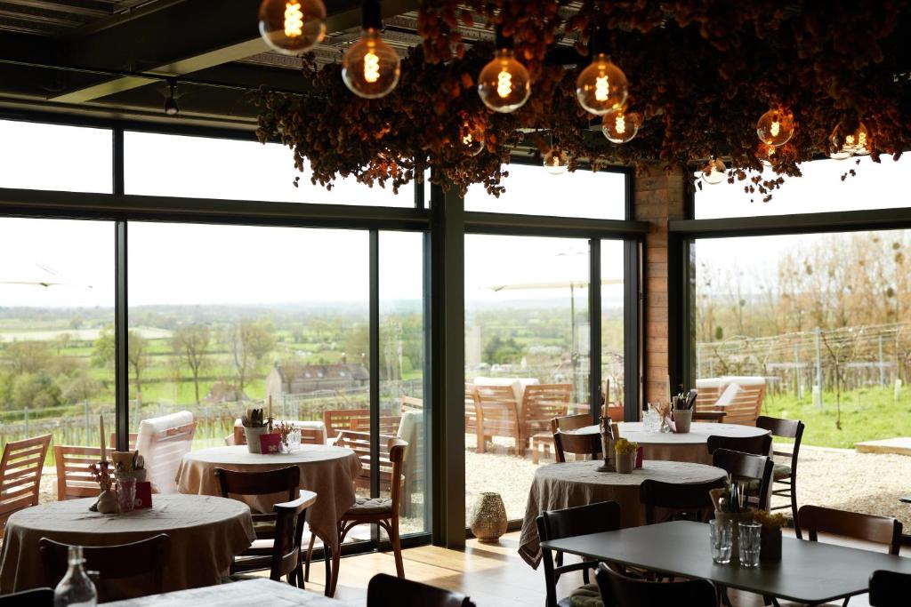 un restaurante con mesas, sillas y ventanas grandes en Vine Cottage, en Shepton Mallet
