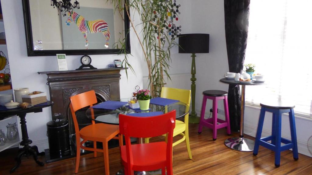 a dining room with colorful chairs and a table at Bamboo Guesthouse in Bournemouth