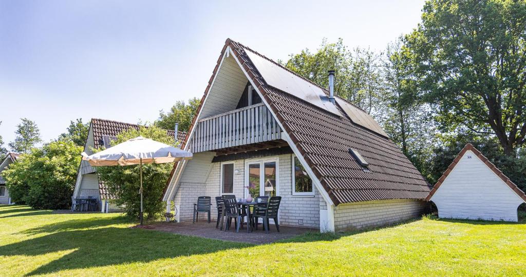 a house with a table and chairs in the yard at De Waterlelie gezellig en sfeervol aan het water in Gramsbergen