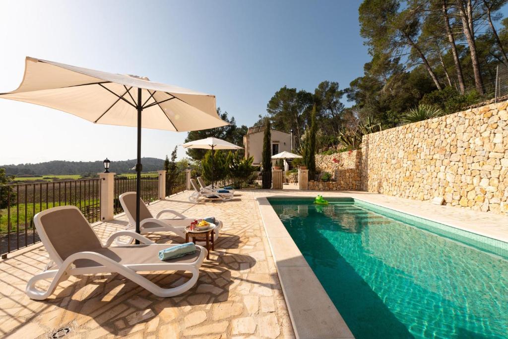 einen Pool mit 2 Stühlen und einem Sonnenschirm in der Unterkunft Eco Finca Can Alegria with Pool in Llucmajor