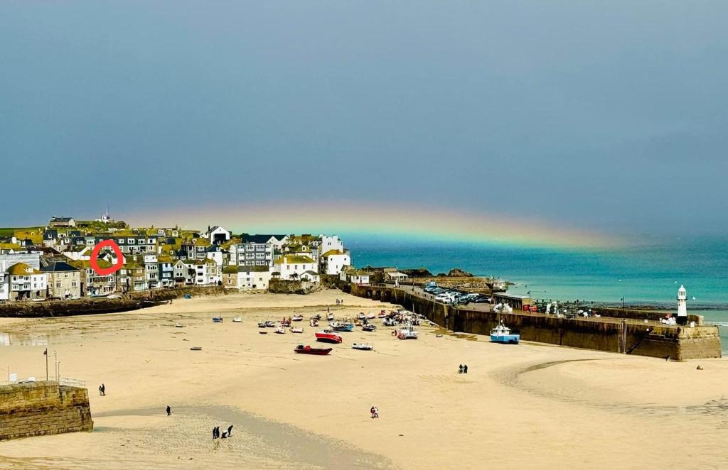 a group of people on a beach with a rainbow at AMAZING LOCATION - "SMUGGLERS HIDE" & "SMUGGLERS CABIN" - a 2 BEDROOM FISHERMANS COTTAGE with HARBOUR VIEW and also a private entrance 1 BED STUDIO - 10 Metres To Sea Front - BOOK BOTH for ENTIRE 3 BEDROOM COTTAGE - 2023 GLOBAL REFURBISHMENT AWARD WINNER in St Ives