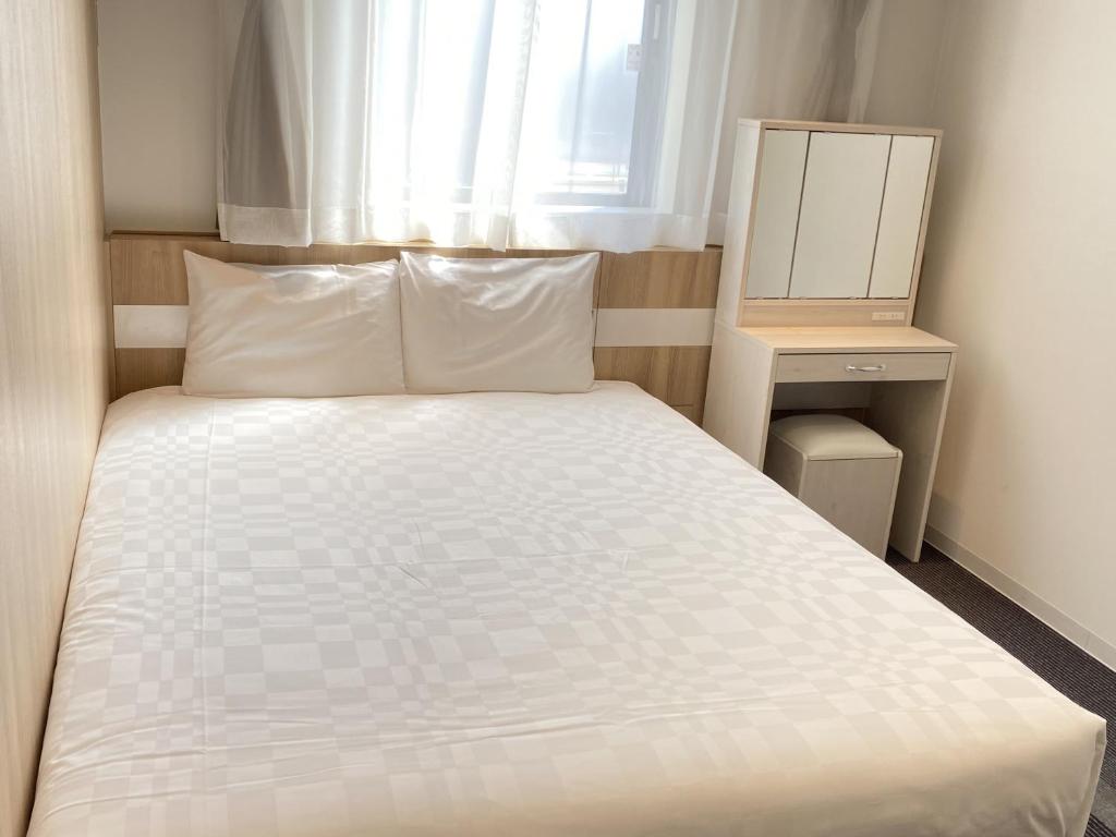 1 dormitorio con cama blanca y ventana en Henn na Hotel Komatsu Ekimae en Komatsu