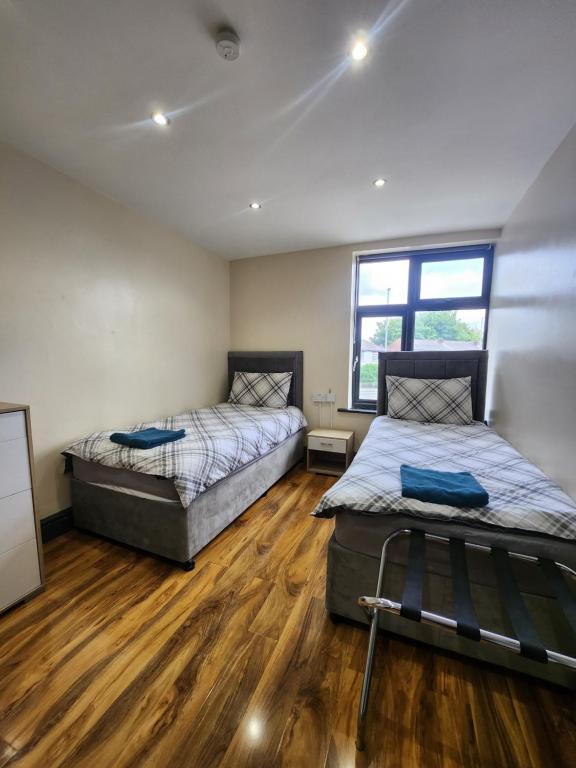 two beds in a room with wooden floors at 133 A Park Road in Manchester