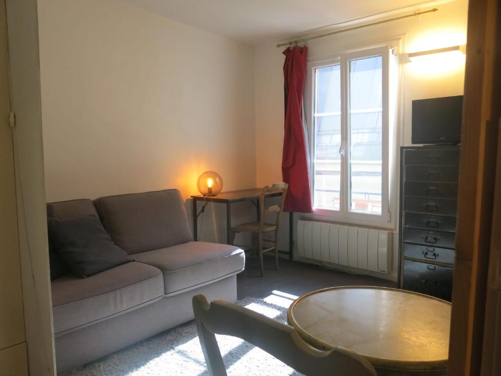 un salon avec un canapé, une table et une fenêtre dans l'établissement Studio Bièvre St Germain CityCosy, à Paris