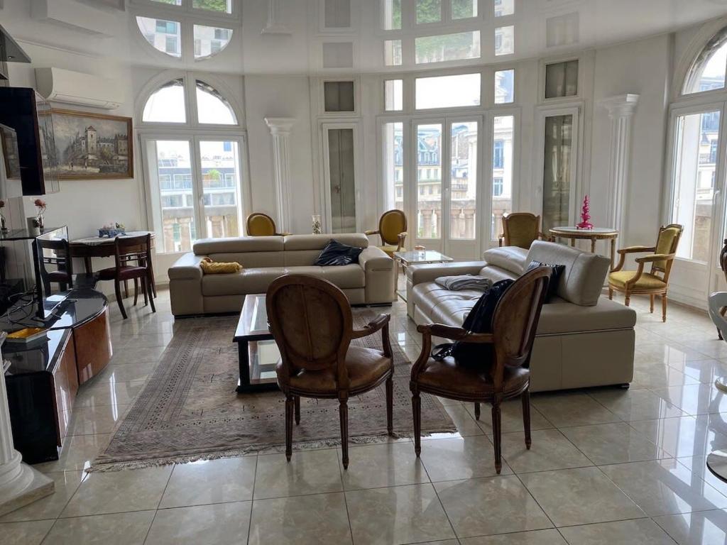 ein Wohnzimmer mit einem Sofa, einem Tisch und Stühlen in der Unterkunft Appartement Opera Chauchat CityCosy in Paris