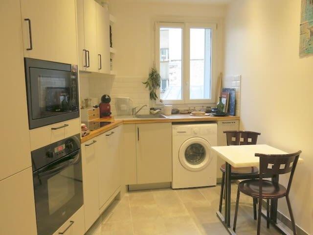 a kitchen with a washing machine and a table with chairs at Appt Letort CityCosy in Paris
