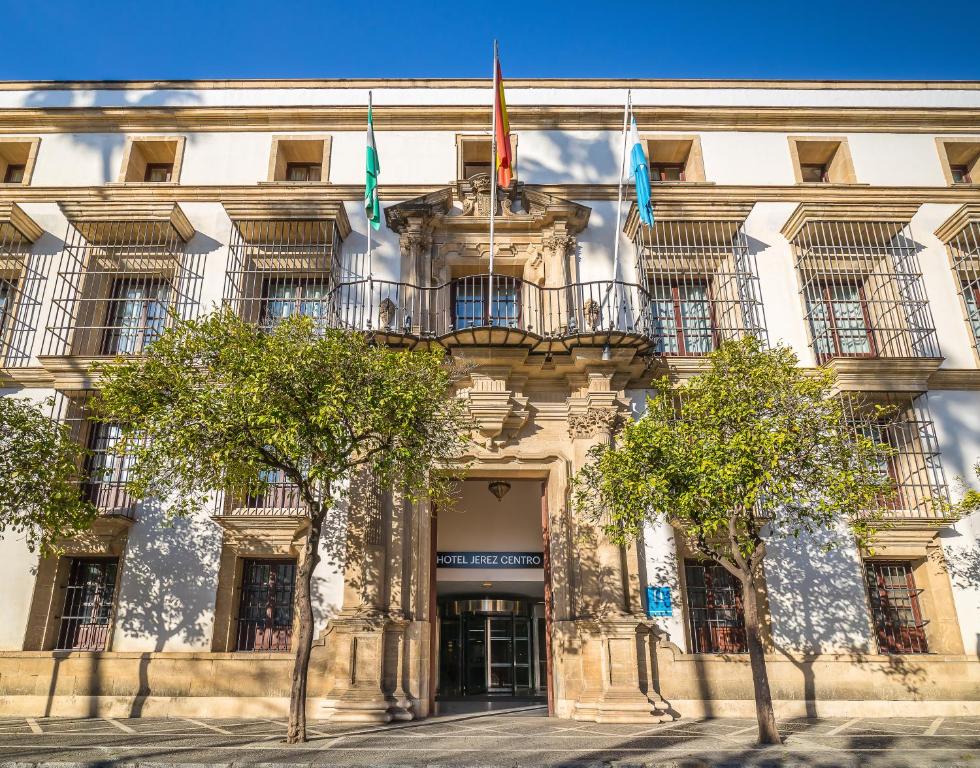 um edifício com três bandeiras à sua frente em Hotel Jerez Centro em Jerez de la Frontera