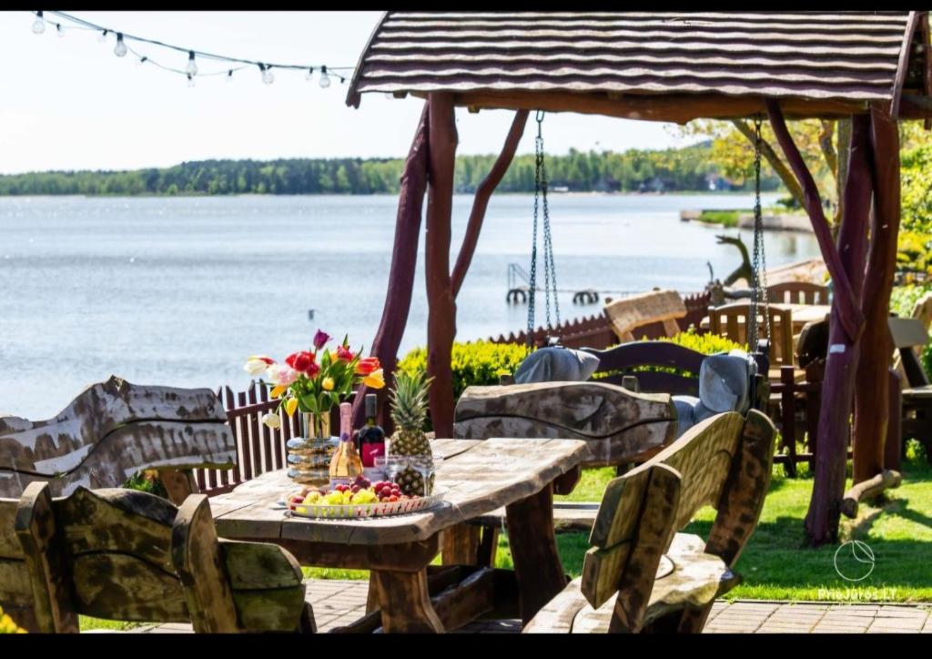 a wooden table with flowers on it next to the water at Preila Kristina-2 in Preila